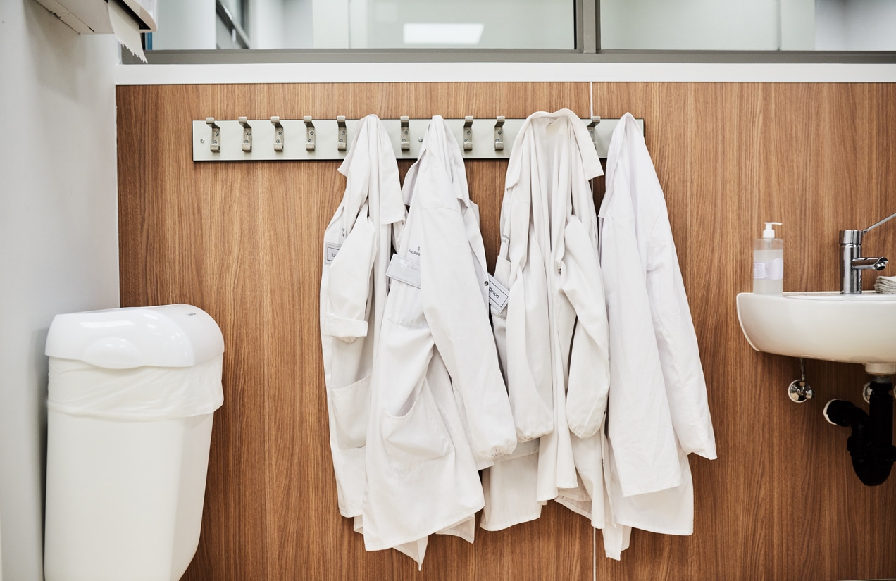 An Empty Bathroom In A Lab With Lab Coats Hanging Up