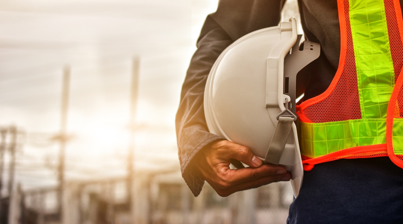 A Technician Holding A White Hard Hat And Wearing A Hi-visibility Vest.